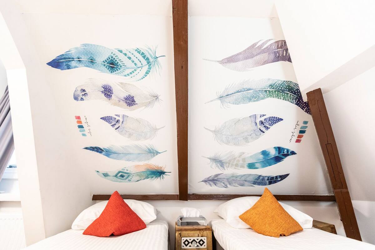 A hotel room with two beds, each with a pillow and a tissue box.