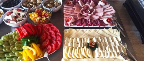 Ein reichhaltiges Buffet mit verschiedenen Speisen, darunter geschnittenes Gemüse, Käse und Fleisch.