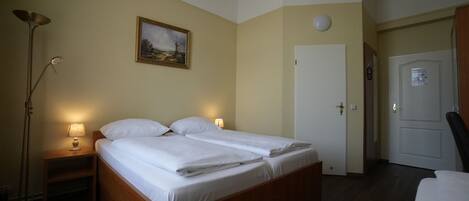 A room with a bed, bedside lamps, a painting, a door, and a lamp on the floor.