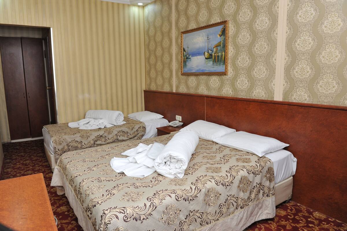 A hotel room with two beds, a wooden headboard, a painting on the wall, and a door.