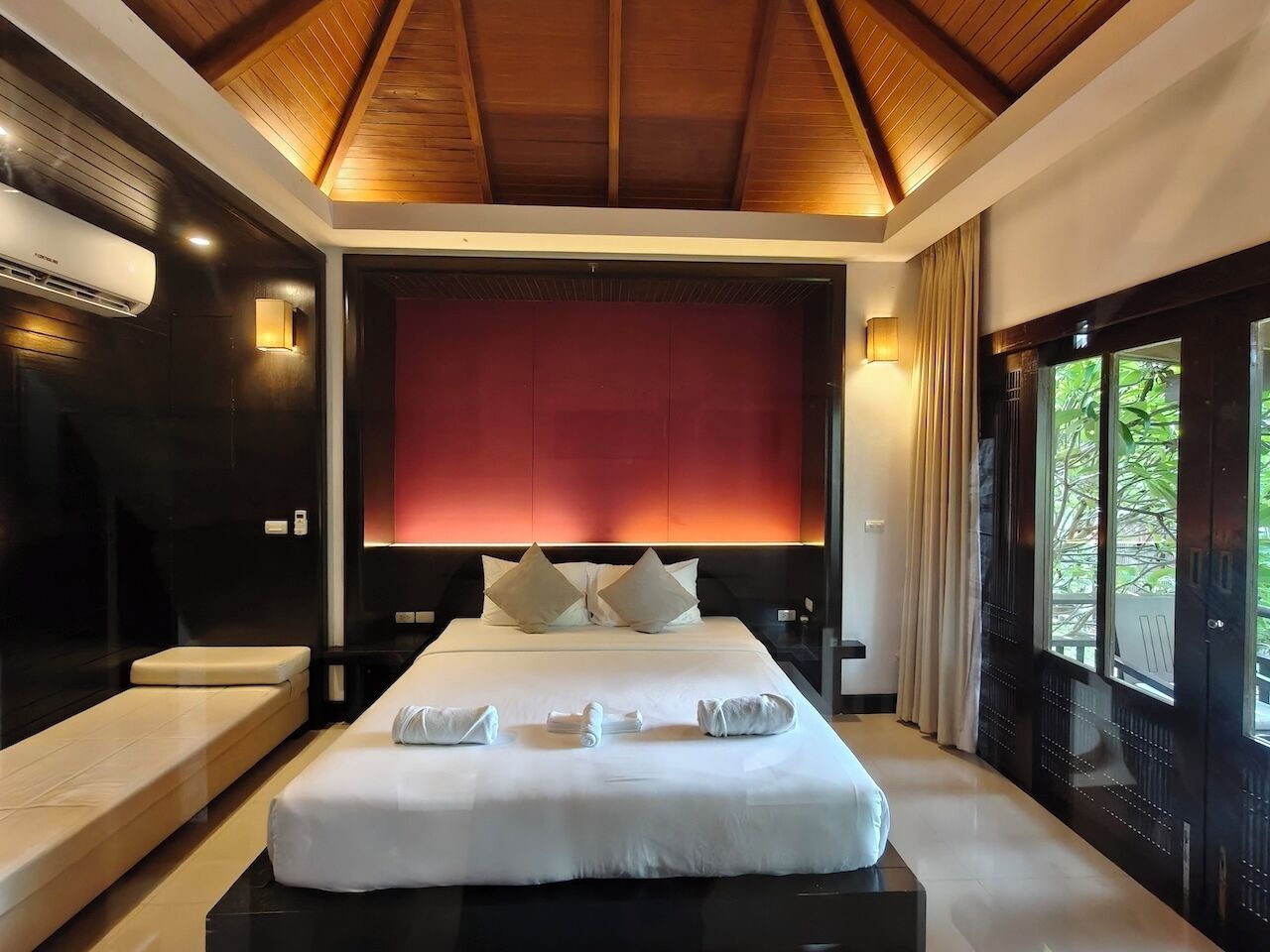 Habitación de hotel moderna con una cama grande, una silla de masaje y vistas a zonas verdes.