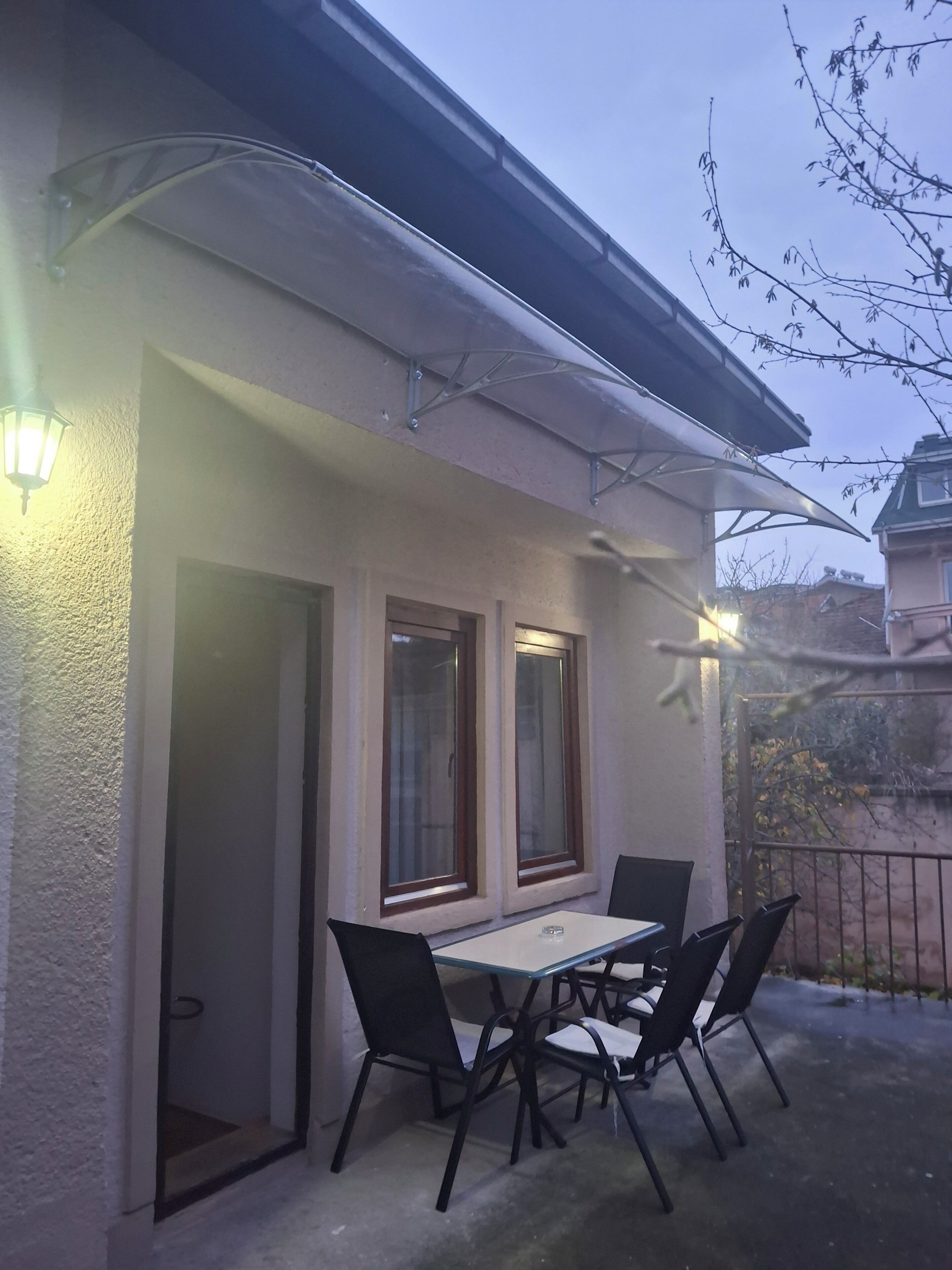 Une terrasse avec une table et des chaises, une lampe et une fenêtre.