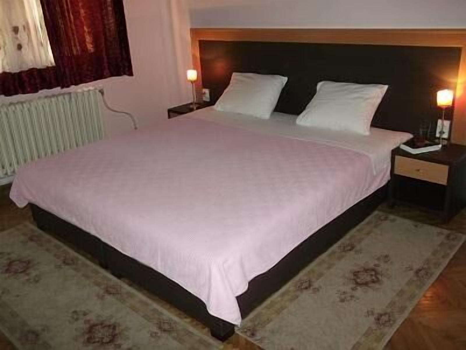A standard hotel room with a bed, nightstands, and a bedside lamp.