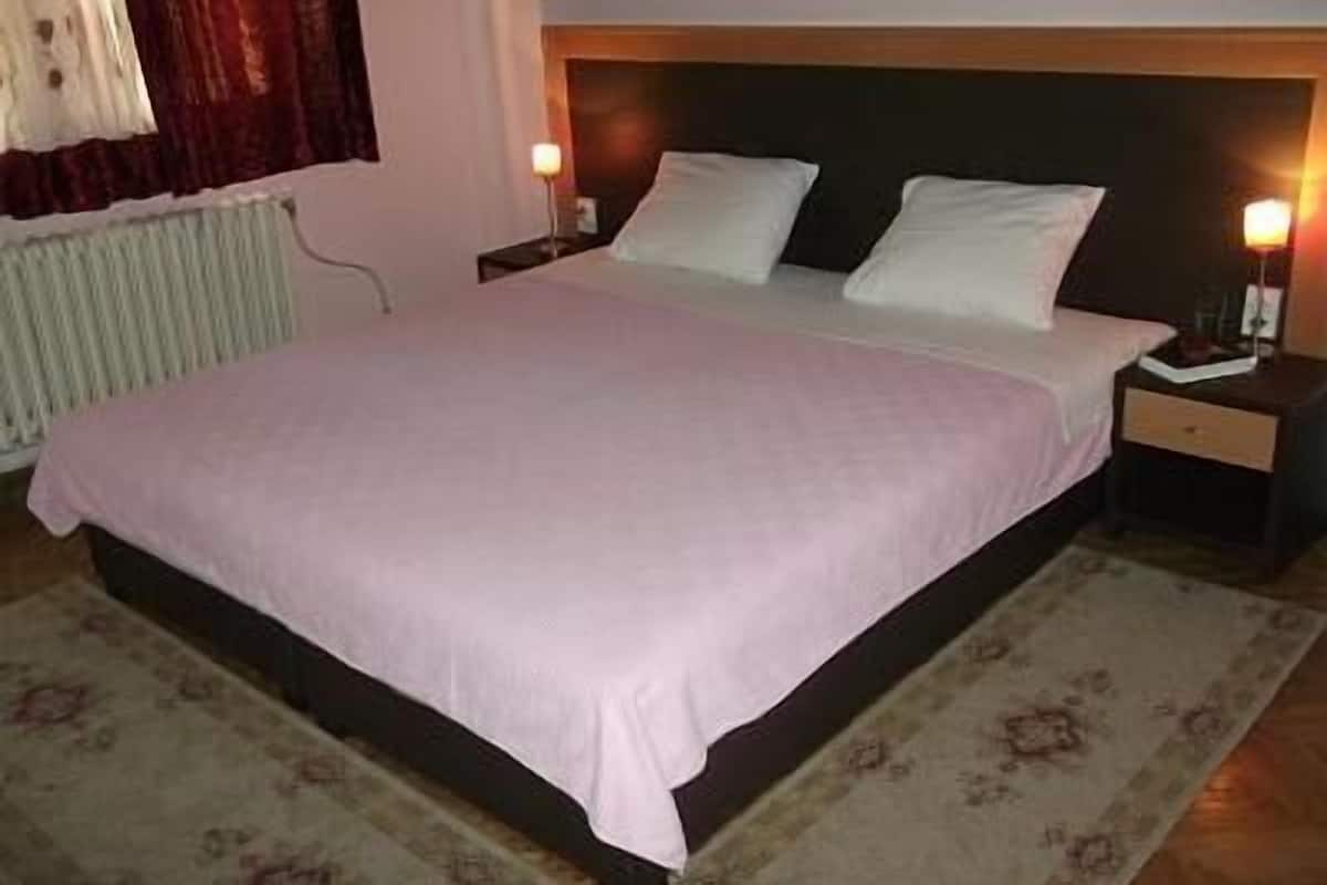 Une chambre d’hôtel standard, équipée d’un lit, de tables de chevet et d’une lampe de chevet.