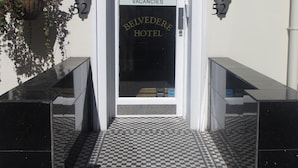 A hotel entrance with a checkered floor, a reception sign, and a sign indicating vacancies. - Belvedere Hotel (London)