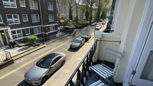 A residential street with parked cars, a building with multiple windows, and a clear sky. - Belvedere Hotel (London)
