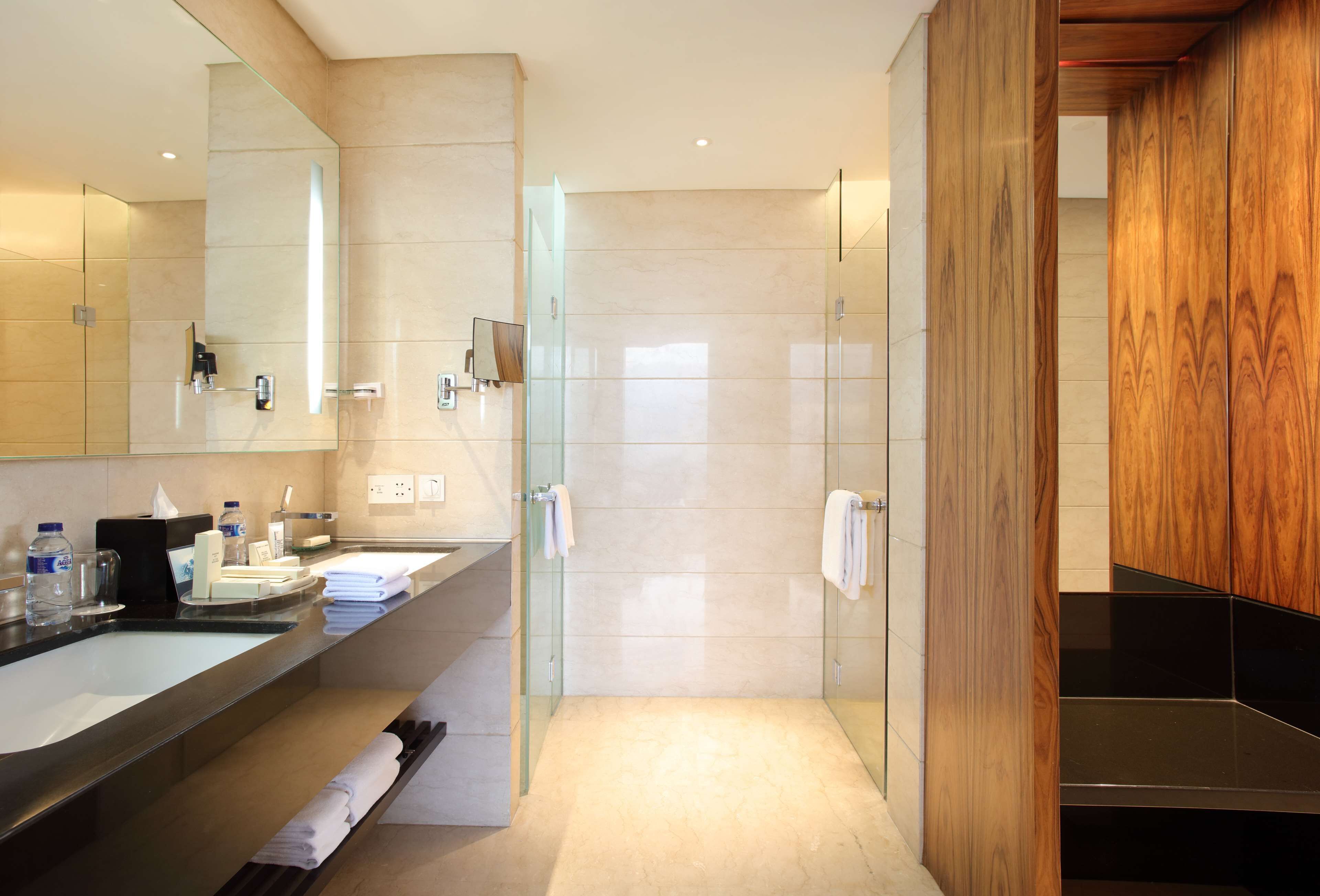 A modern bathroom with a glass shower enclosure, a vanity with a mirror, and a wooden cabinet.