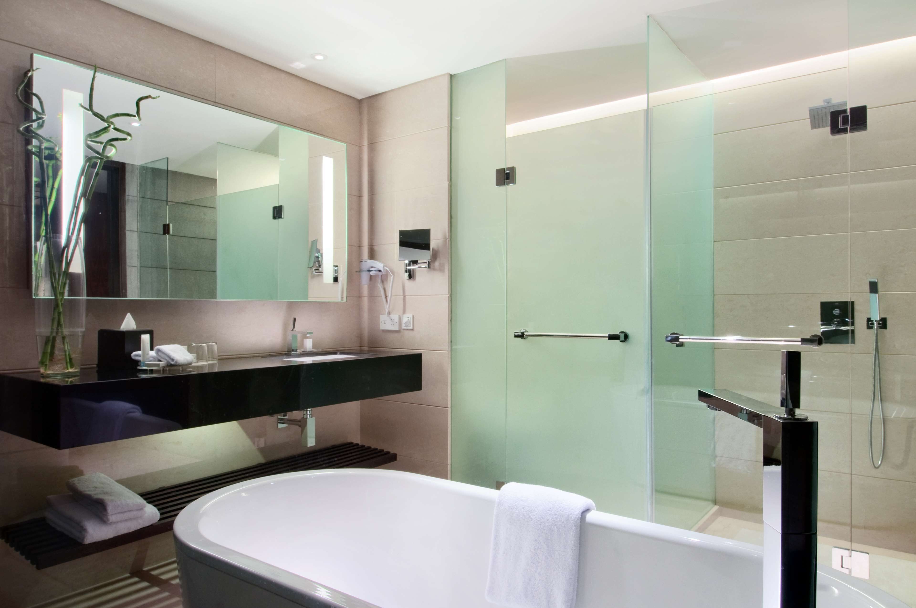 Un baño moderno con cabina de ducha de vidrio, una bañera independiente y un lavamanos con espejo.