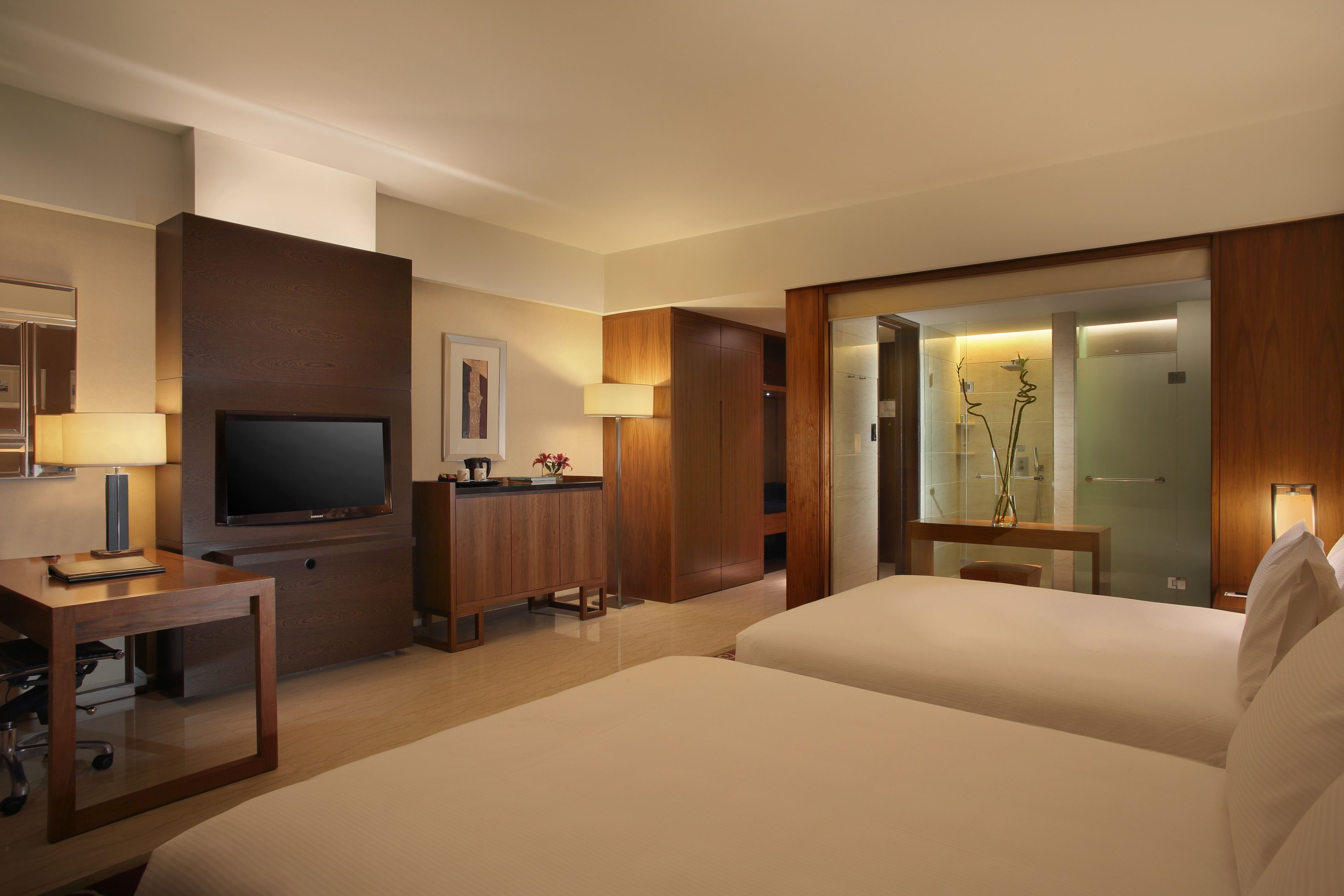 A hotel room with a TV, a desk, a bed, and a bathroom visible through an open door.