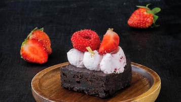 Un postre sobre un plato de madera con fresas y crema batida.