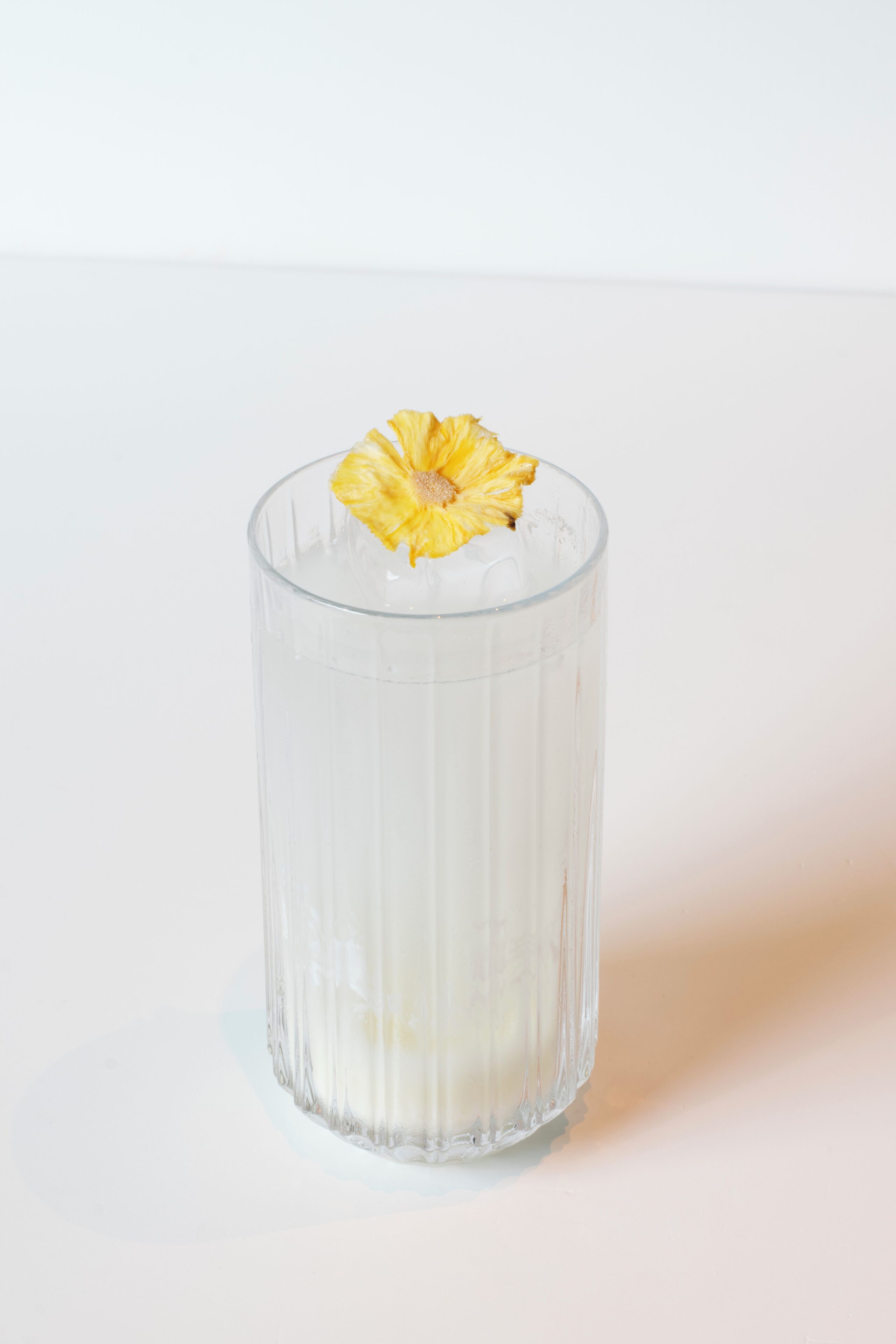 A clear glass with a yellow flower garnish.