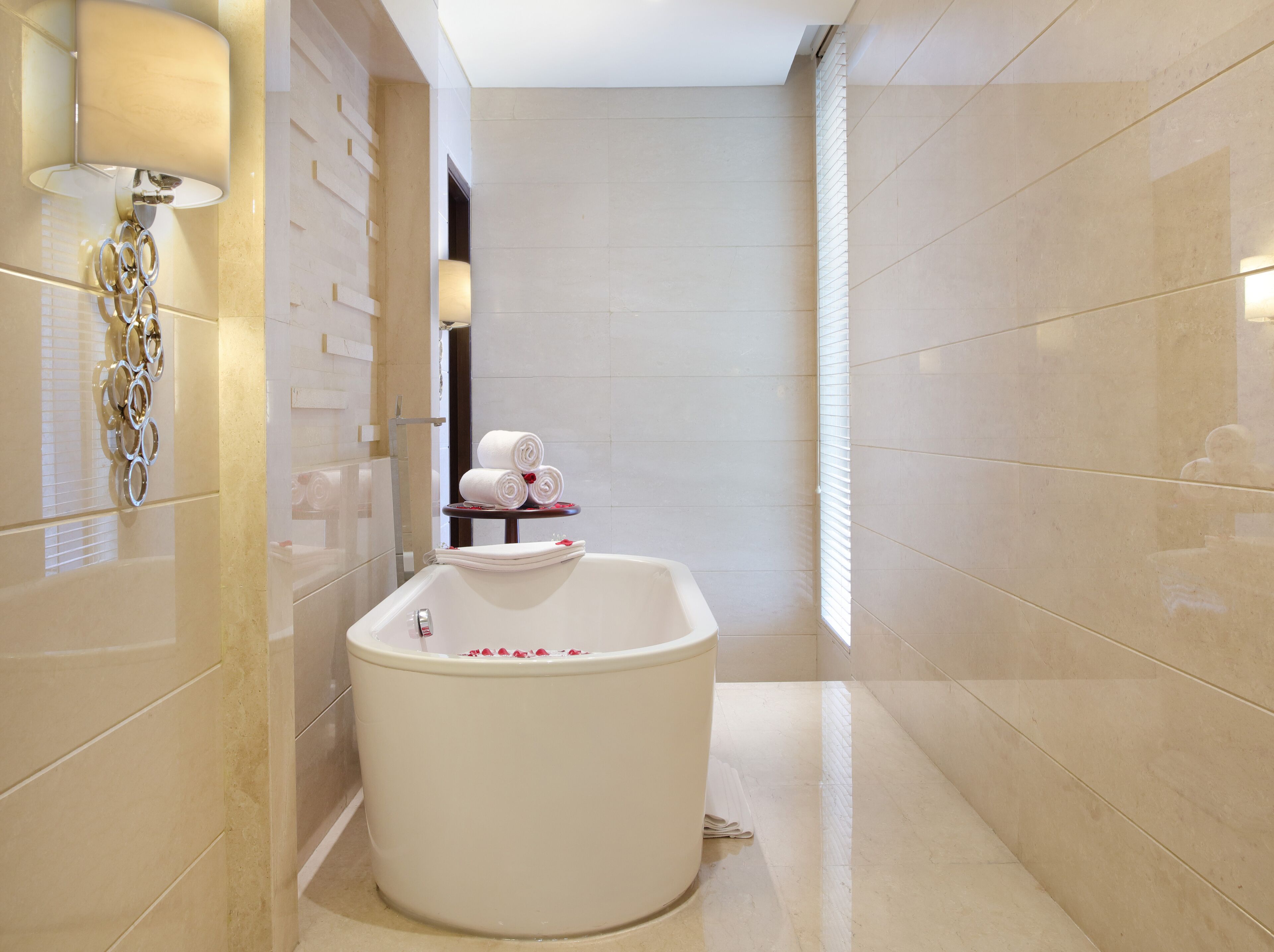 A modern bathroom with a freestanding bathtub, a towel rack, and a mirror.