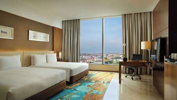 A hotel room with two beds, a desk, a chair, a TV, and a large window with a city view.