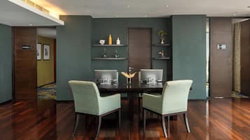 Un salón de conferencias con una mesa de madera oscura, dos sillas verde claro y una decoración moderna con estantes empotrados.