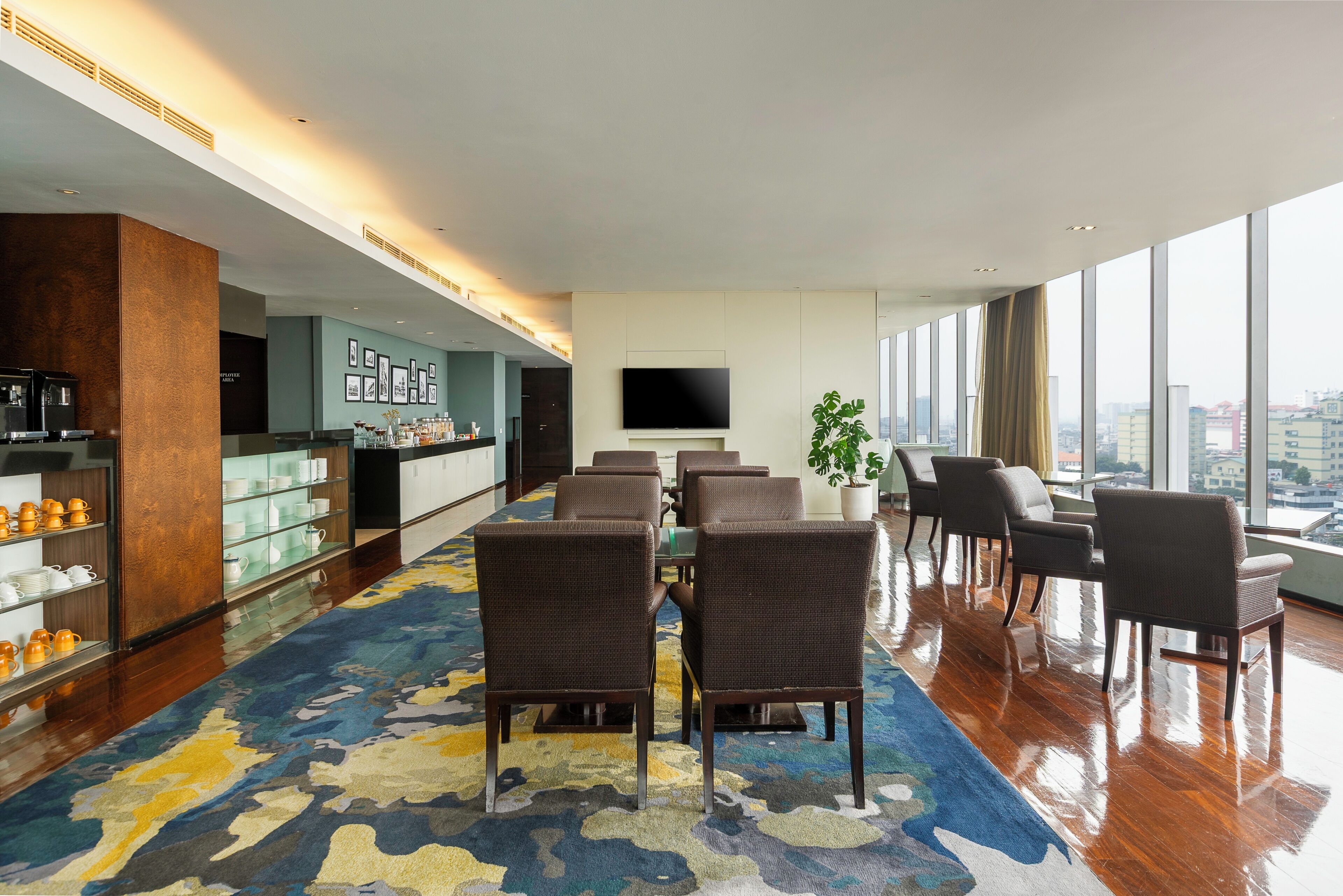 A hotel lobby with a seating area, a bar, and a large window offering a city view.
