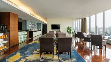 A hotel lobby with a seating area, a bar, and a large window offering a city view.
