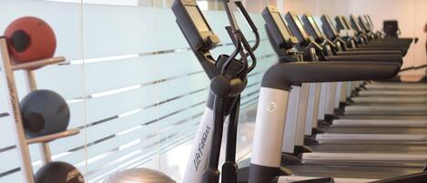 A row of stationary bikes with a mirrored wall behind them.