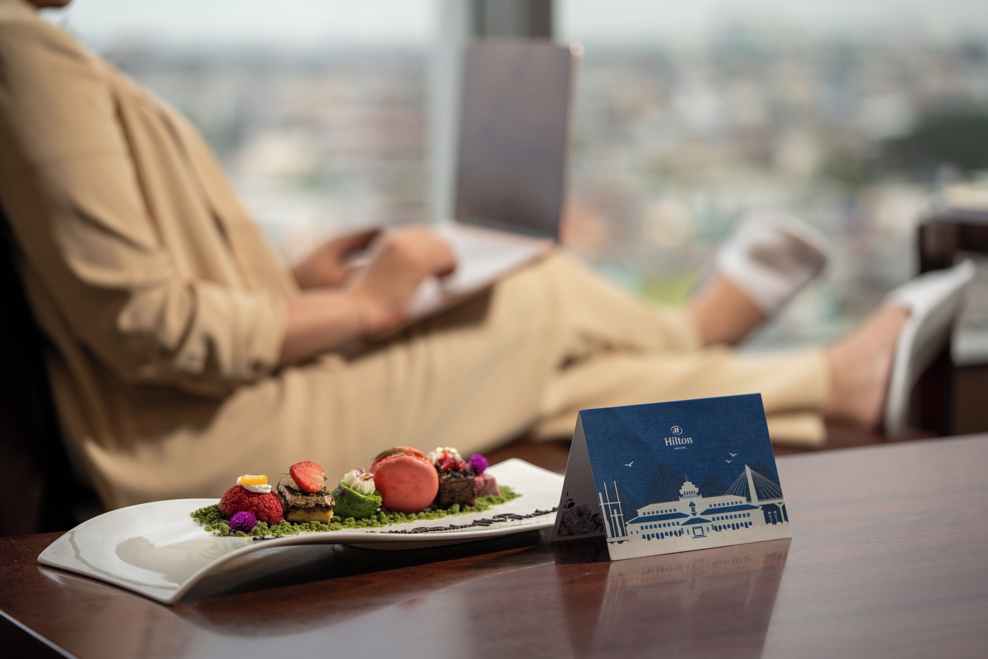 A person seated at a table with a plate of food and a Hilton-branded card.