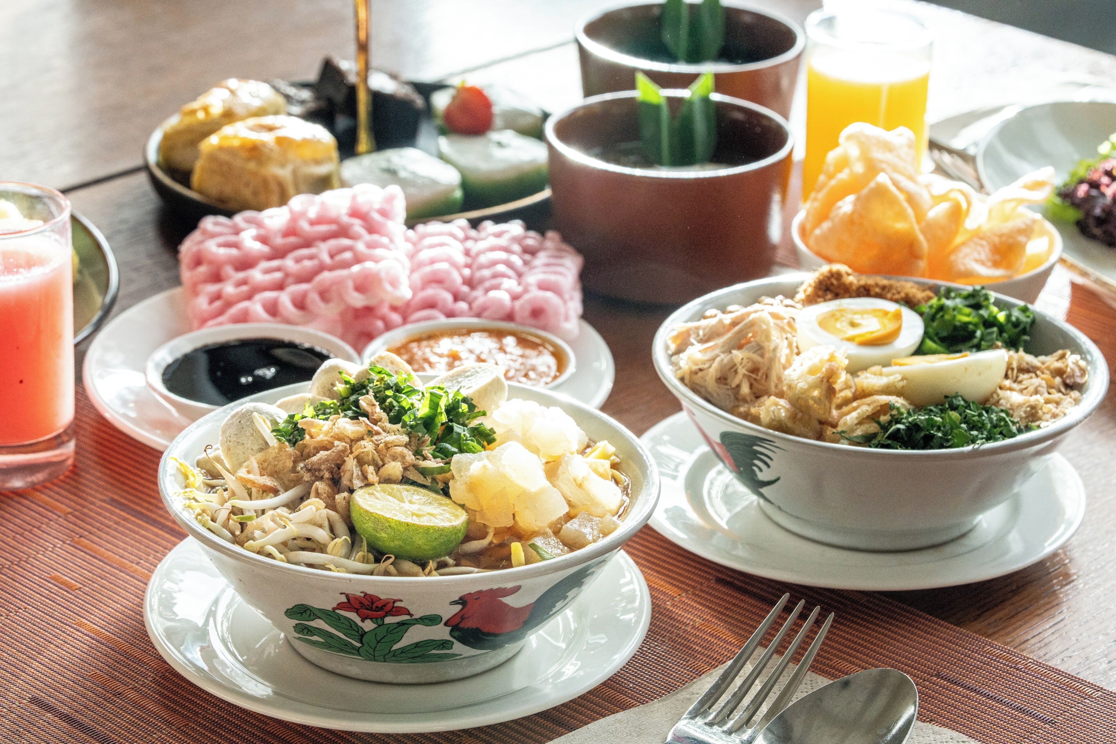 A table with various dishes, including bowls of food, a glass of orange juice, and a cup of tea.