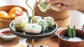Una bandeja escalonada con diversos pasteles y una mano eligiendo uno.