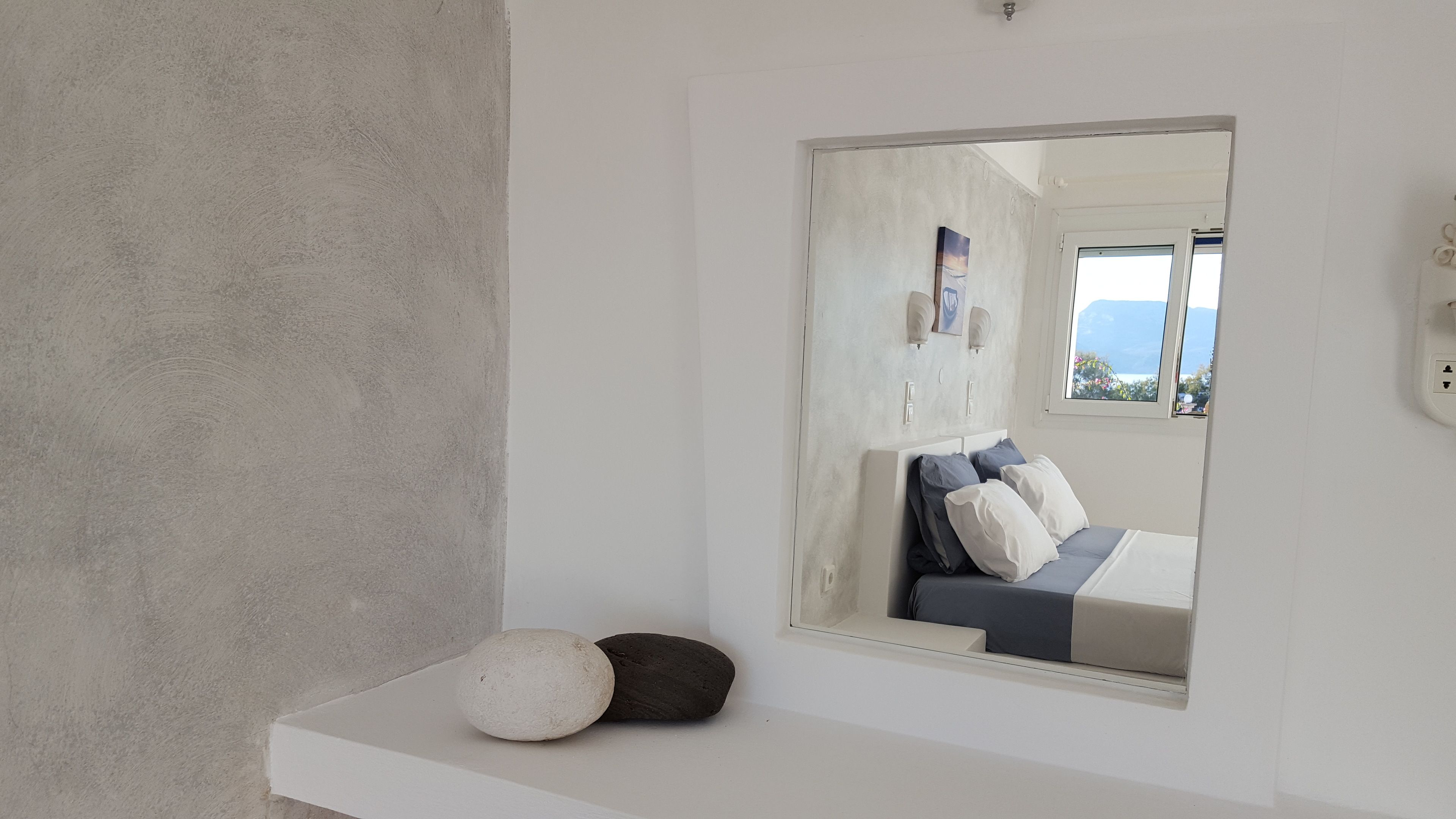 A modern bathroom with a large mirror, a white countertop, and a bed with blue and white bedding.