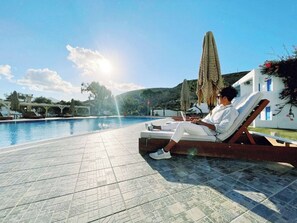 A poolside area with a lounge chair and a person relaxing. - Lagada Beach Hotel (Milos)