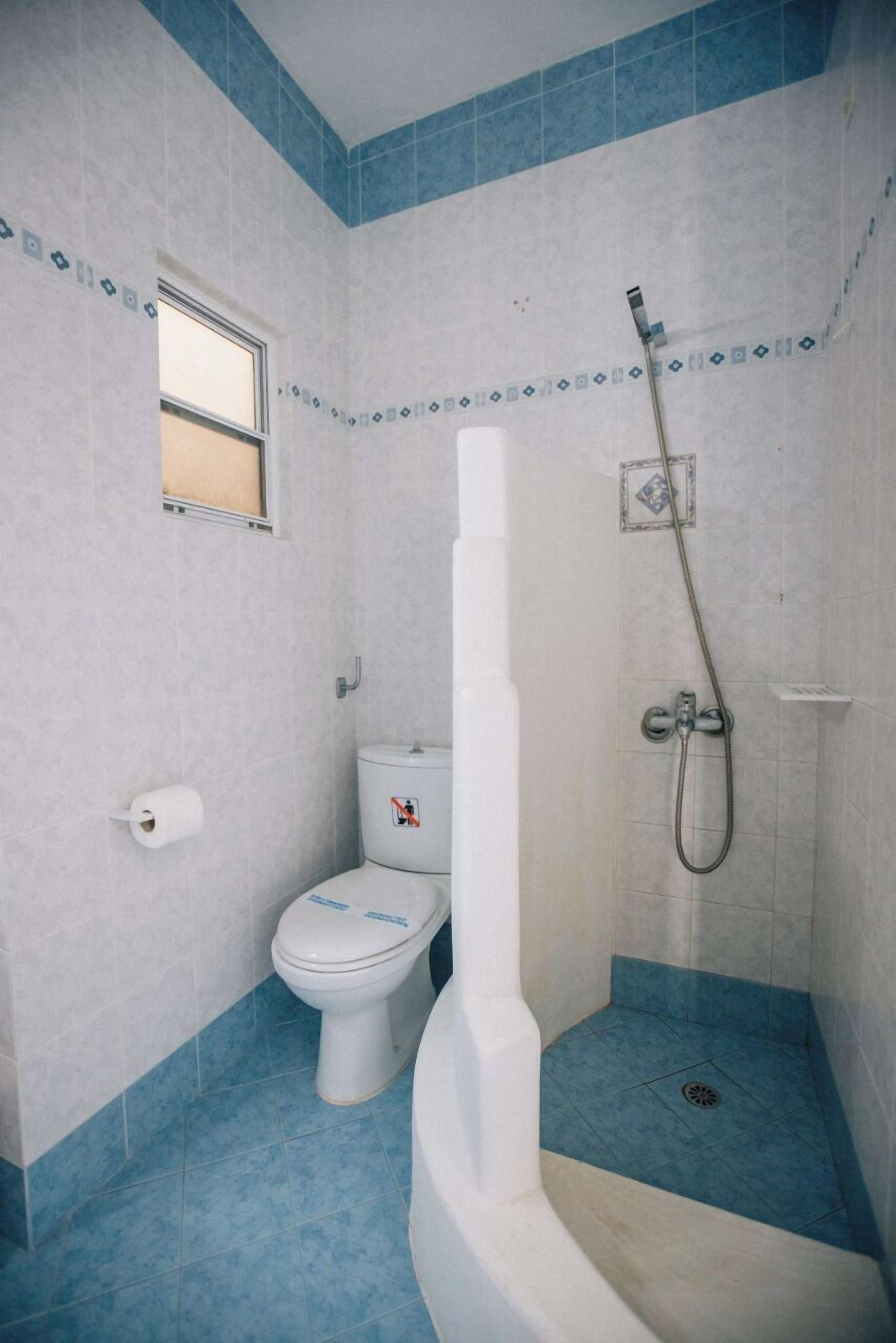 Un baño con inodoro, ducha y una pequeña ventana.