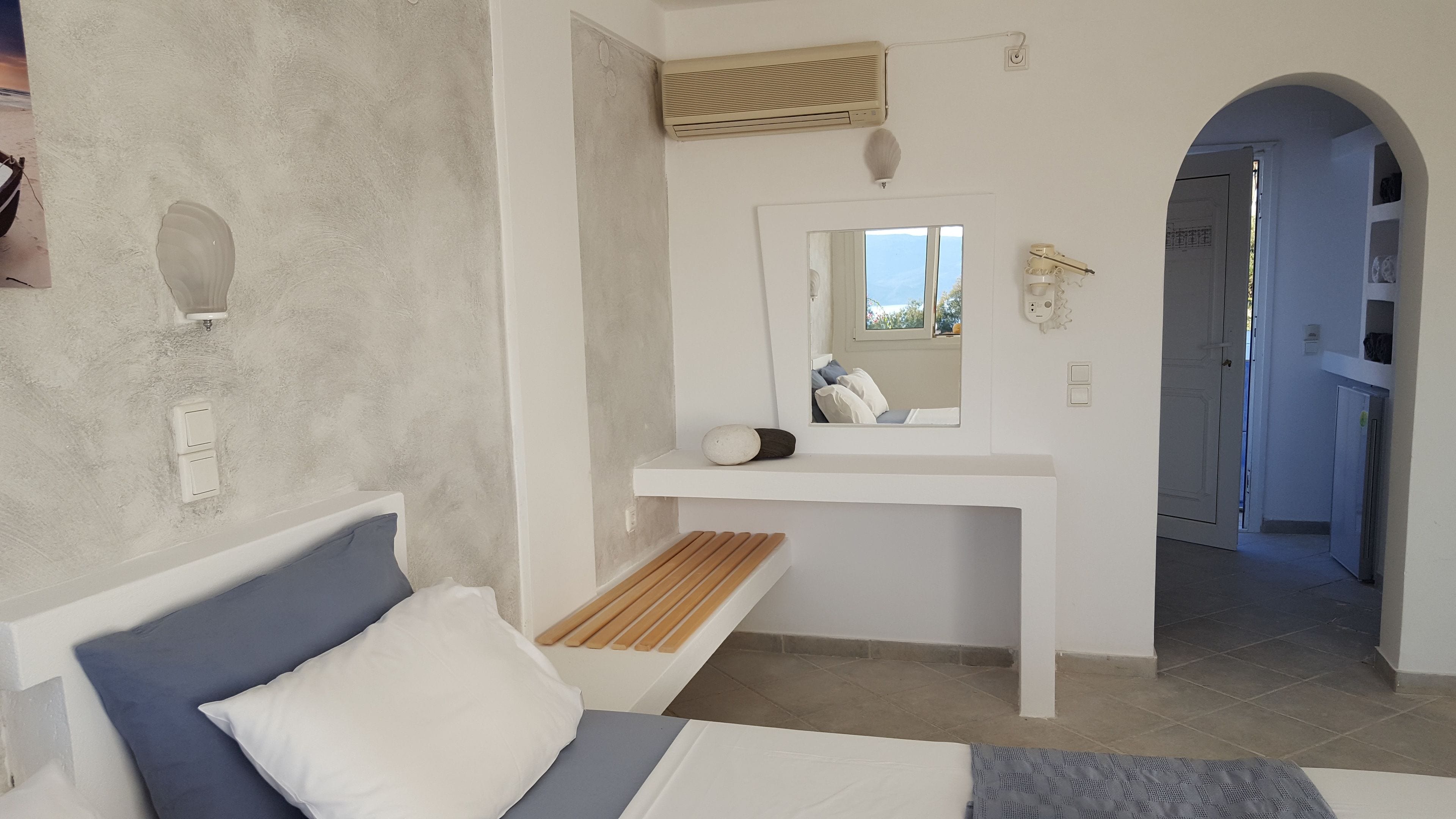 Ein Schlafzimmer mit Bett, Nachttisch, Spiegel und Fenster.