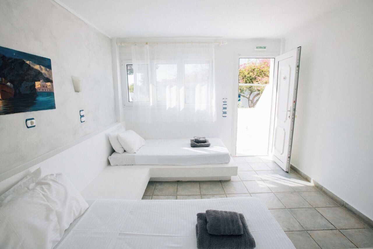 A minimalist hotel room with a bed, a small seating area, and a painting on the wall.
