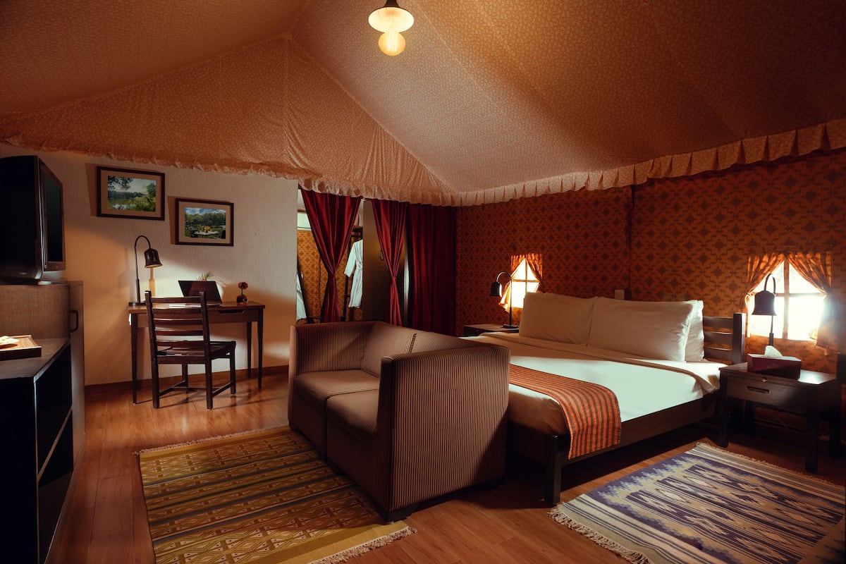 Et hyggeligt hotelværelse med seng, sofa, skrivebord og fjernsyn.