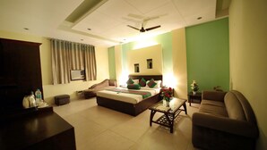 A hotel room with a bed, a sofa, a coffee table, and a TV. - Hotel Blue Bell (New Delhi)