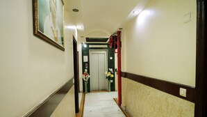 A hallway with a marble floor, a framed portrait on the left, and a door at the end. - Hotel Blue Bell (New Delhi)