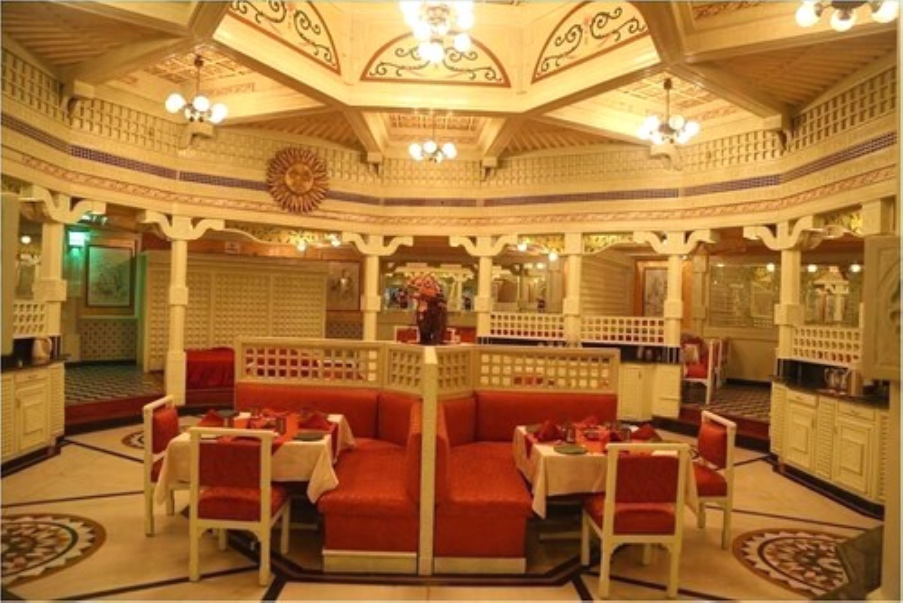 A traditional interior with ornate ceiling designs, seating arrangements, and a central decorative element.