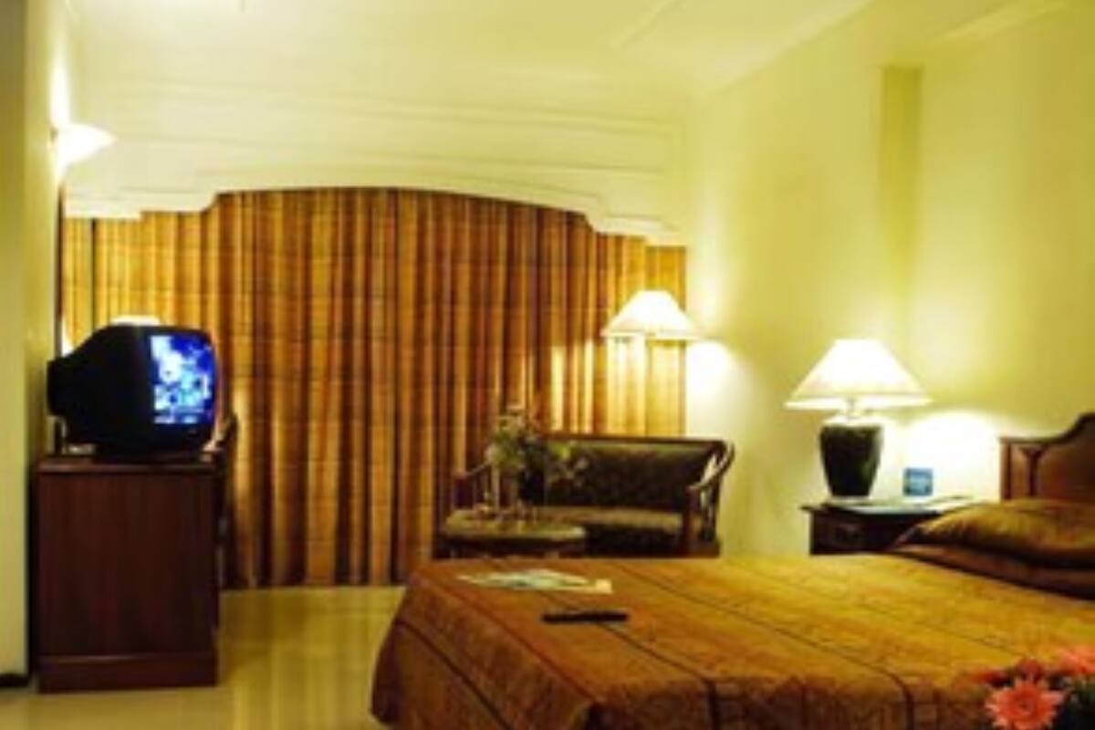 A hotel room with a bed, a television, a chair, and two lamps.