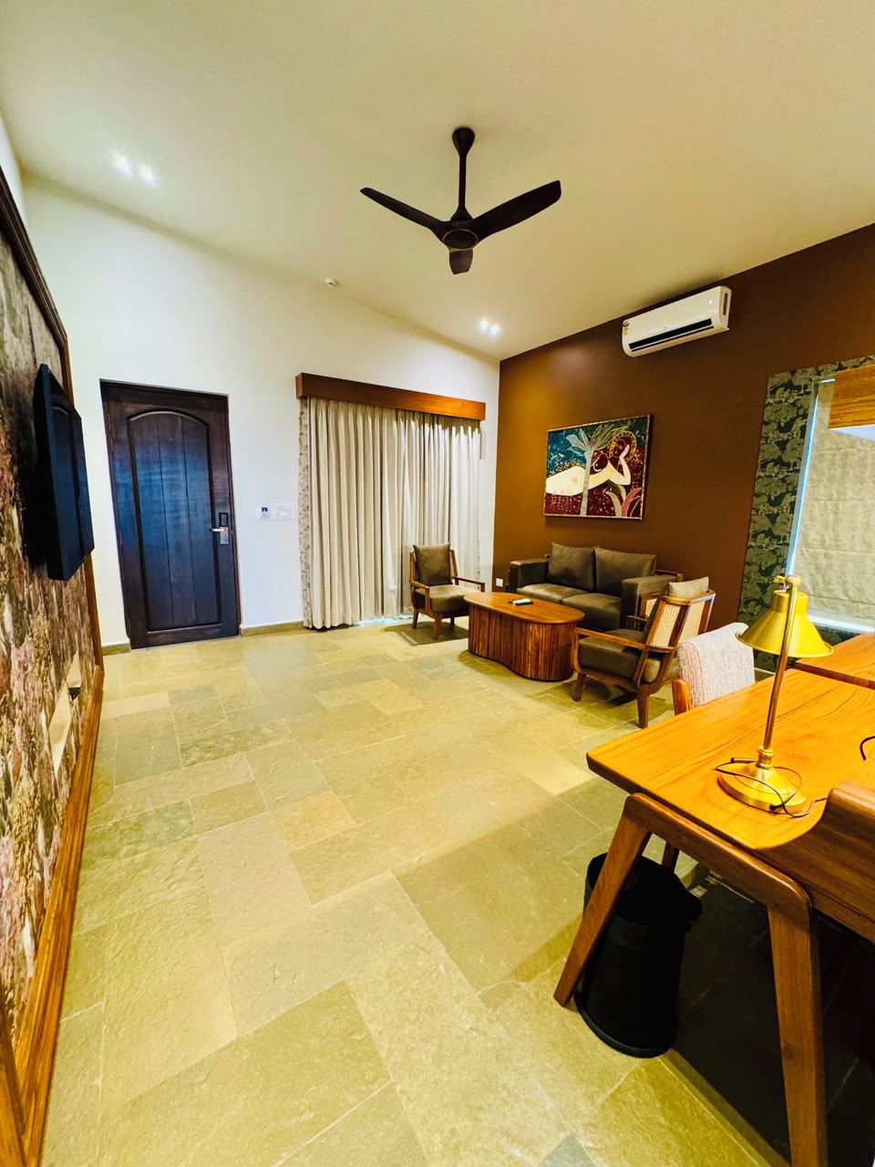 A spacious living area with a sofa set, a coffee table, a TV, and a ceiling fan.