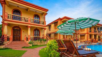 A large, two-story building with a swimming pool, outdoor seating, and a well-maintained garden.