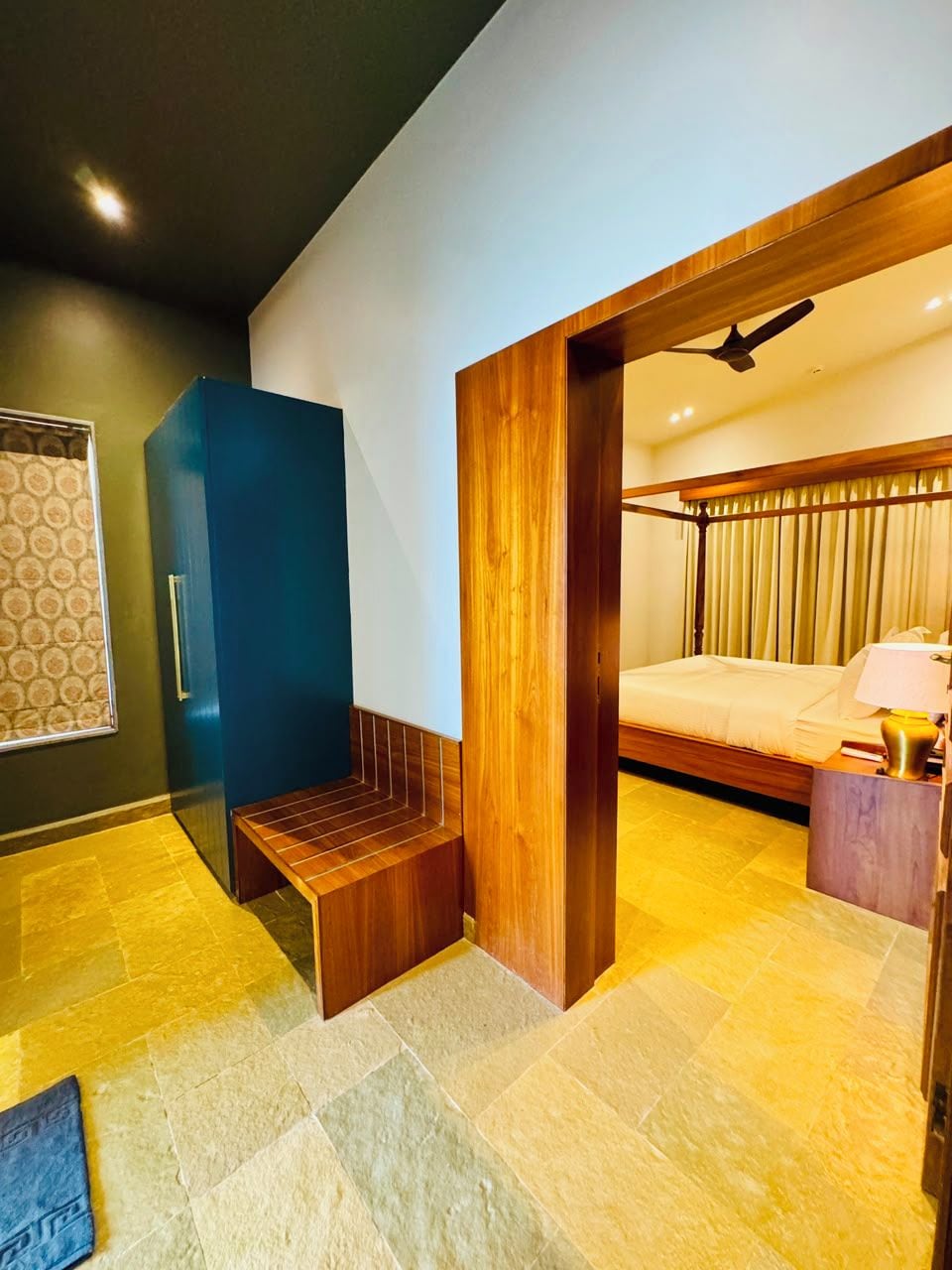 Una habitación de hotel moderna con una cama, un banco, un escritorio y una ventana con cortinas.
