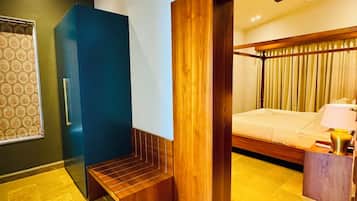 A modern hotel room with a bed, a bench, a desk, and a window with curtains.