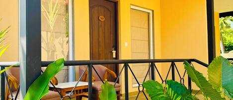 A yellow building with a covered porch, a door, and a railing.