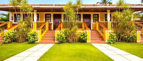 A two-story building with a red-tiled roof, yellow walls, and a central staircase.