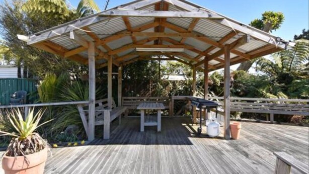 A wooden deck with a covered pavilion, outdoor furniture, and potted plants. - Buller Bridge Motel (Westport)