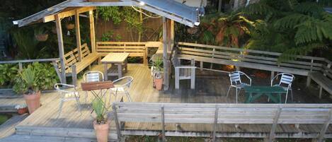 A covered outdoor seating area with wooden furniture and potted plants.
