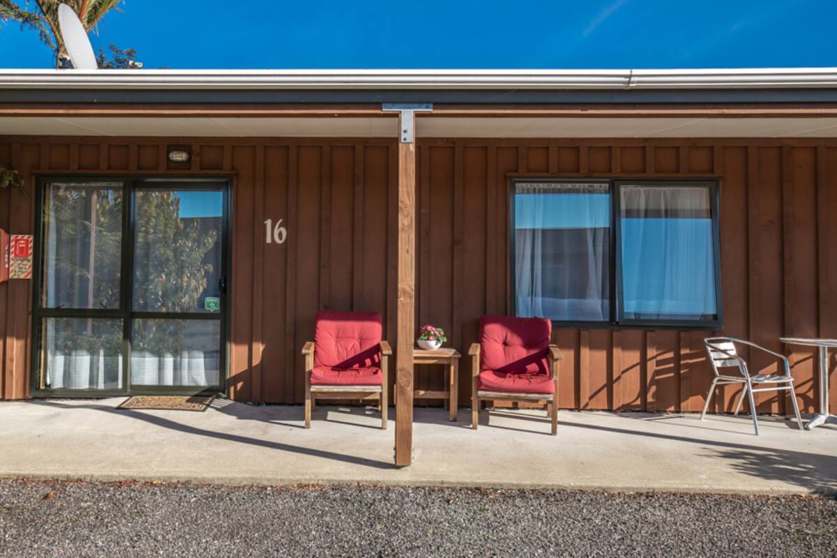 A motel with two red chairs and a small table outside.