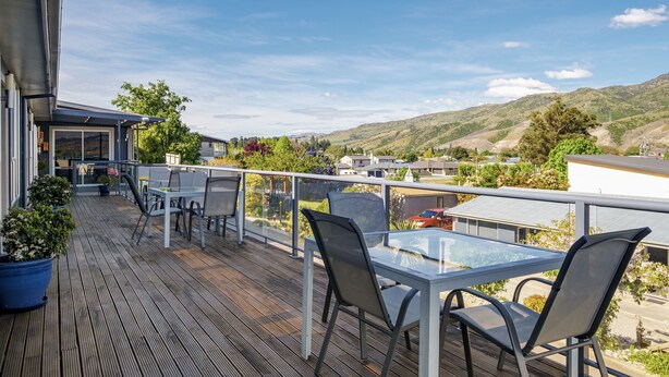 A wooden deck with outdoor seating, overlooking a hilly landscape. - Central Gateway Motel (Cromwell)