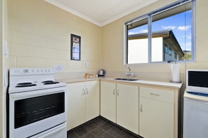 A kitchen with a stove, oven, sink, and window. - Central Gateway Motel (Cromwell)
