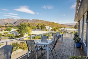 A balcony with a table and chairs, overlooking a mountainous landscape with houses and a hotel sign. - Central Gateway Motel (Cromwell)