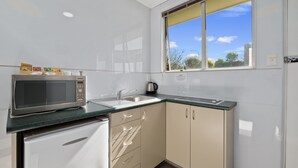 A modern kitchen with a microwave, sink, and cabinets. - Central Gateway Motel (Cromwell)
