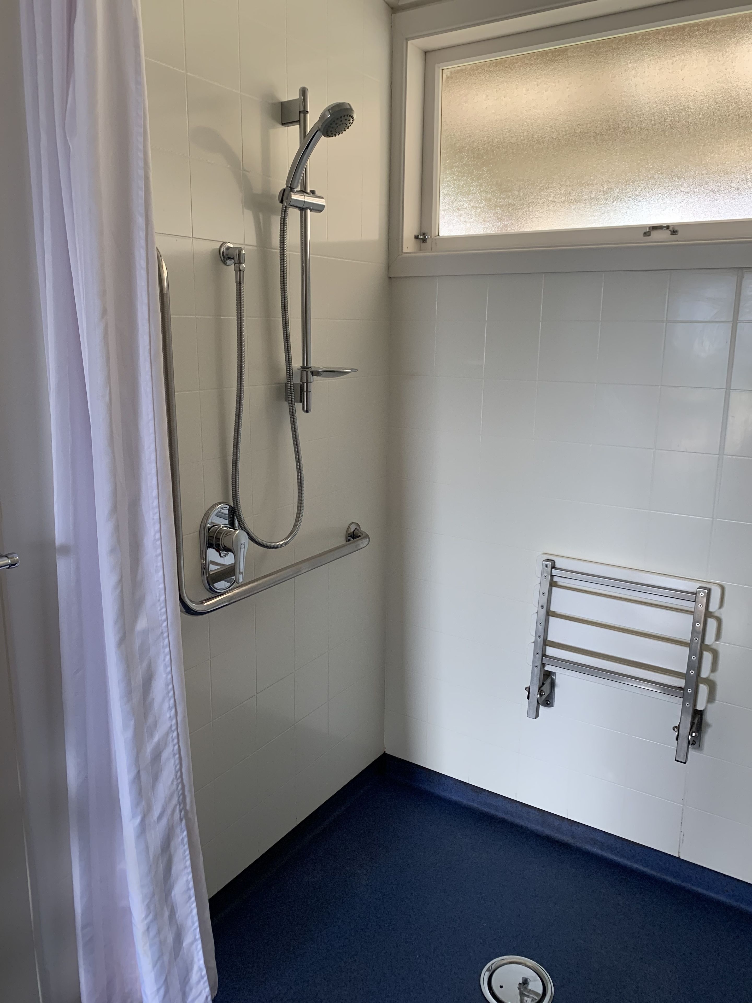 Een douche met een handdouche, een handmatige doucheaansluiting en een handdoekrek aan de muur.