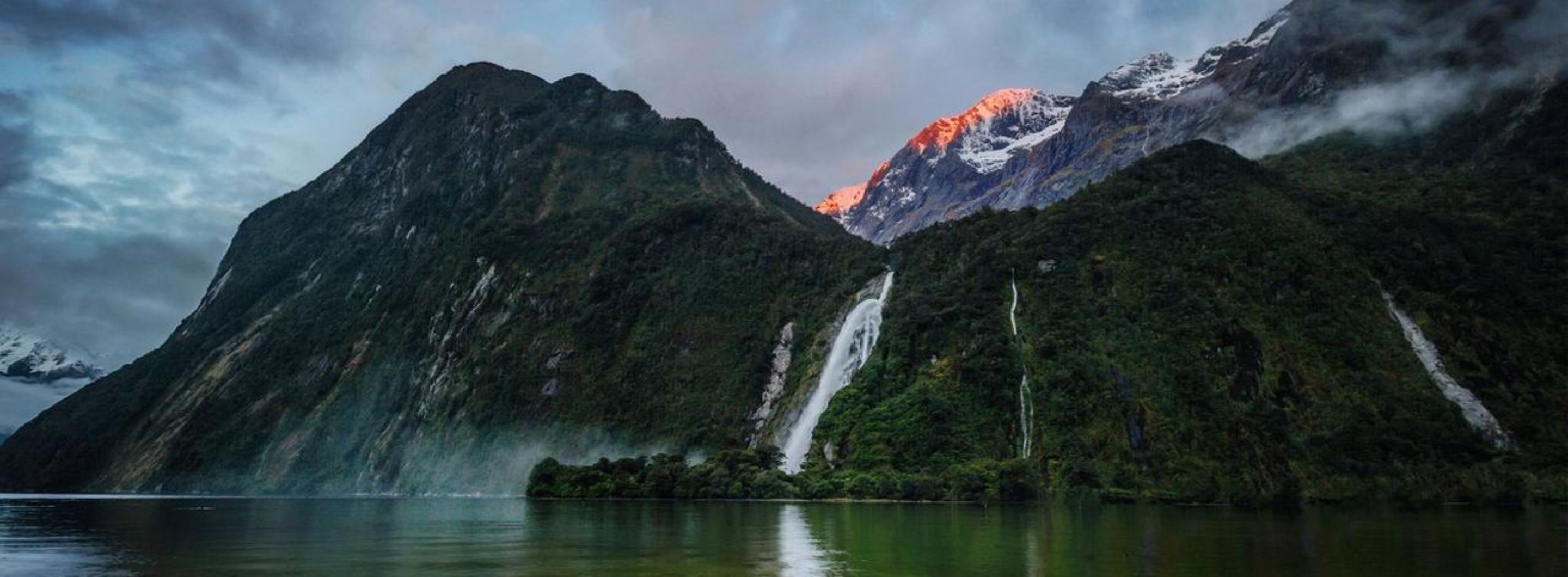A mountainous landscape with waterfalls and a lake.