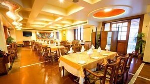 Un restaurante con varias mesas y sillas, suelo de madera e iluminación empotrada en el techo.